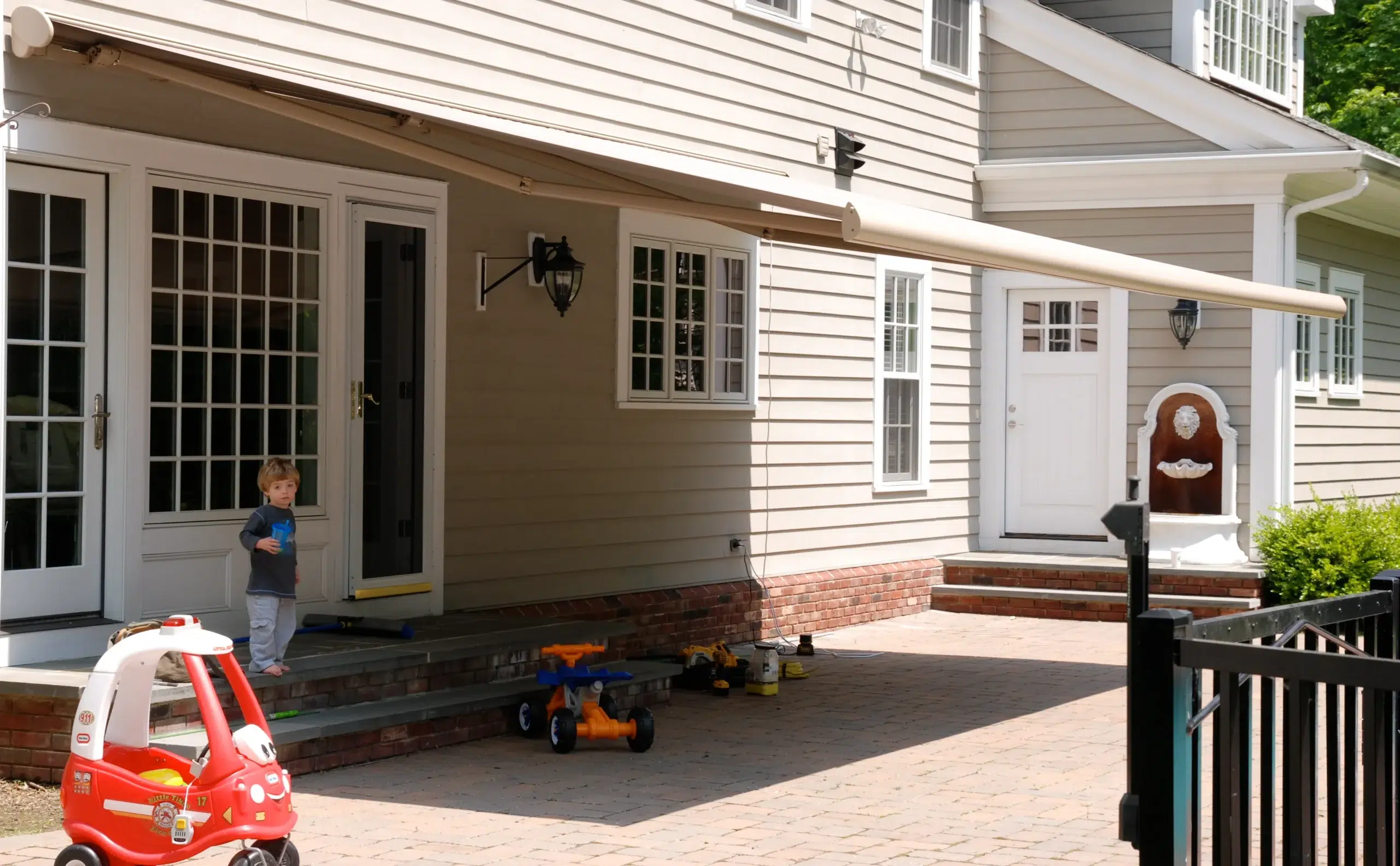 A home with a retractable awning over the patio, offering shade and a stylish outdoor living space for relaxation.