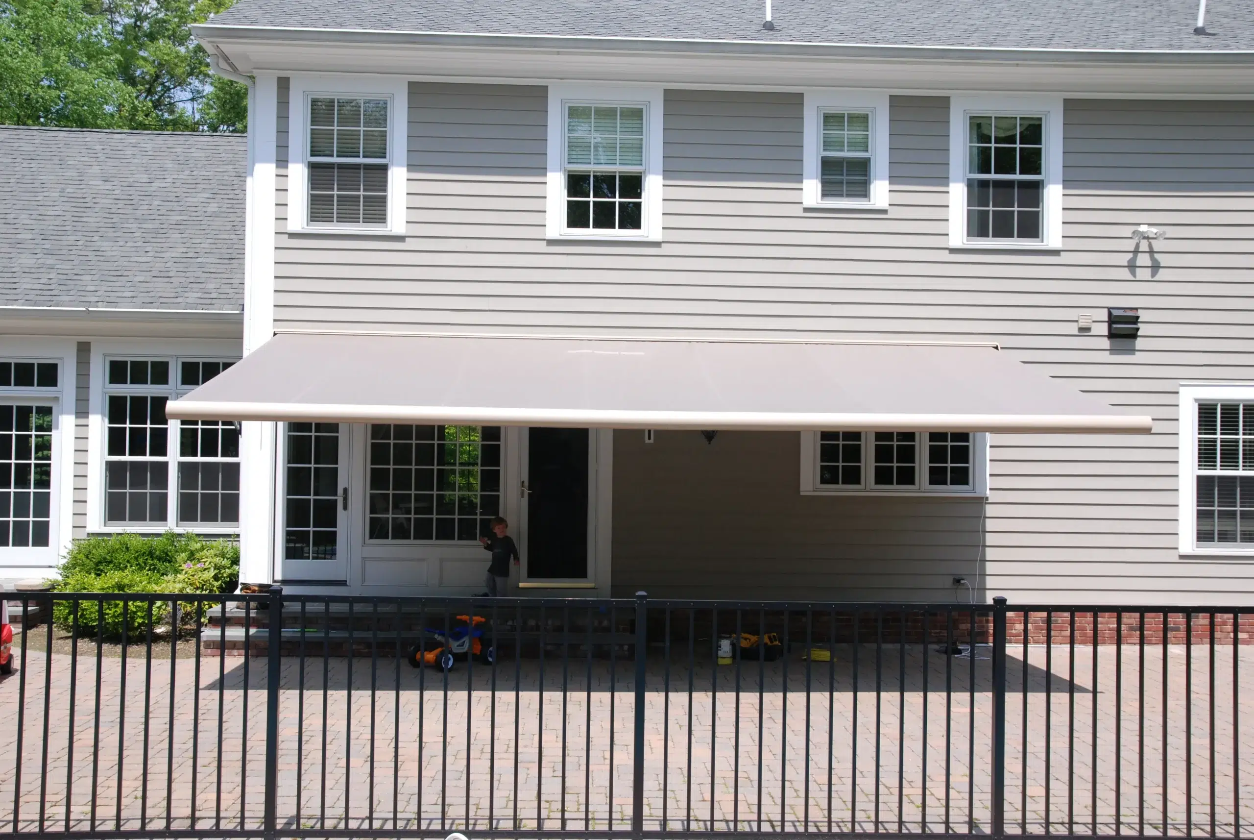 Residential home with a retractable awning over the patio area, providing shade and outdoor comfort.
