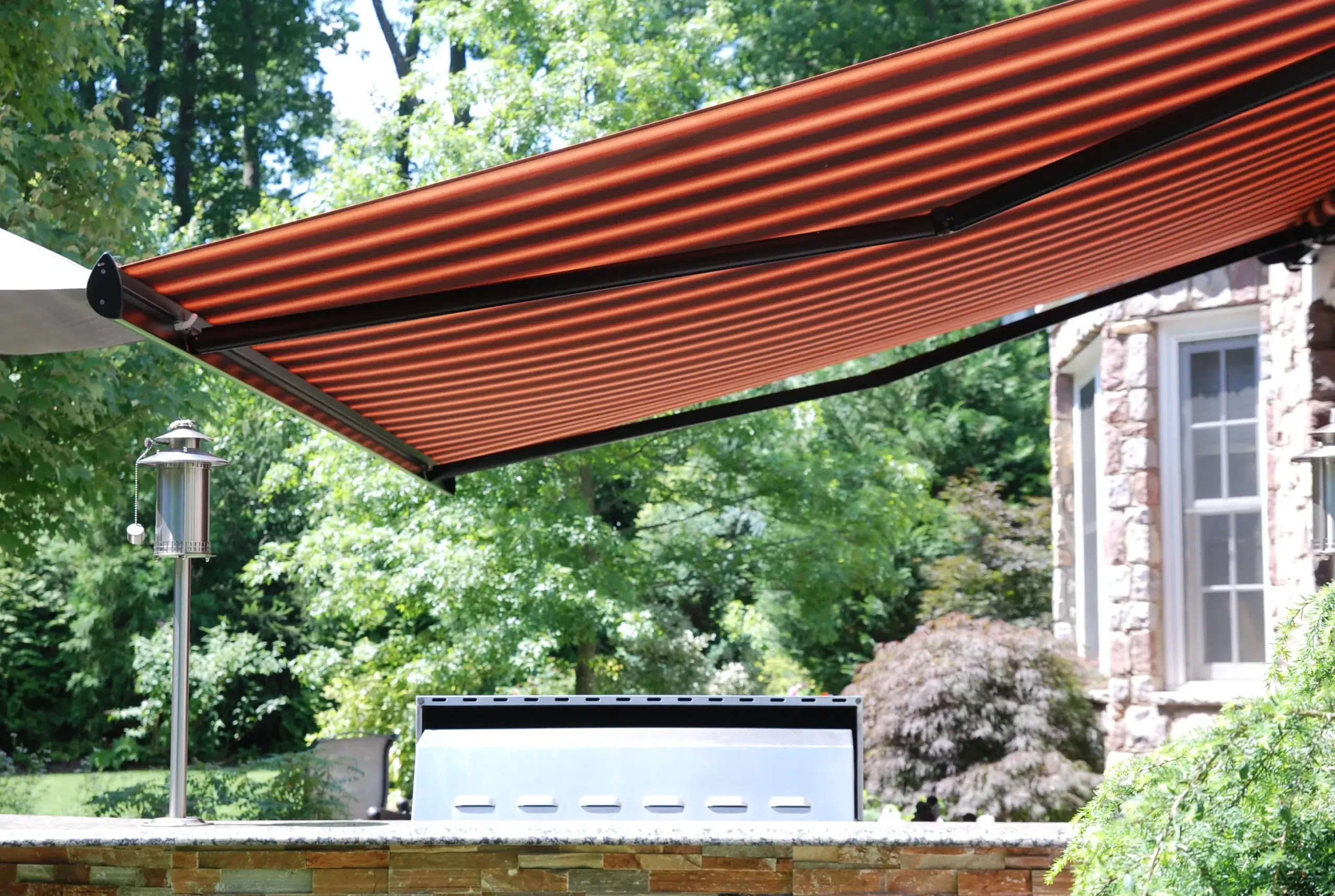 A sleek retractable awning providing shade to a residential patio near a kitchen area, offering a perfect outdoor space.