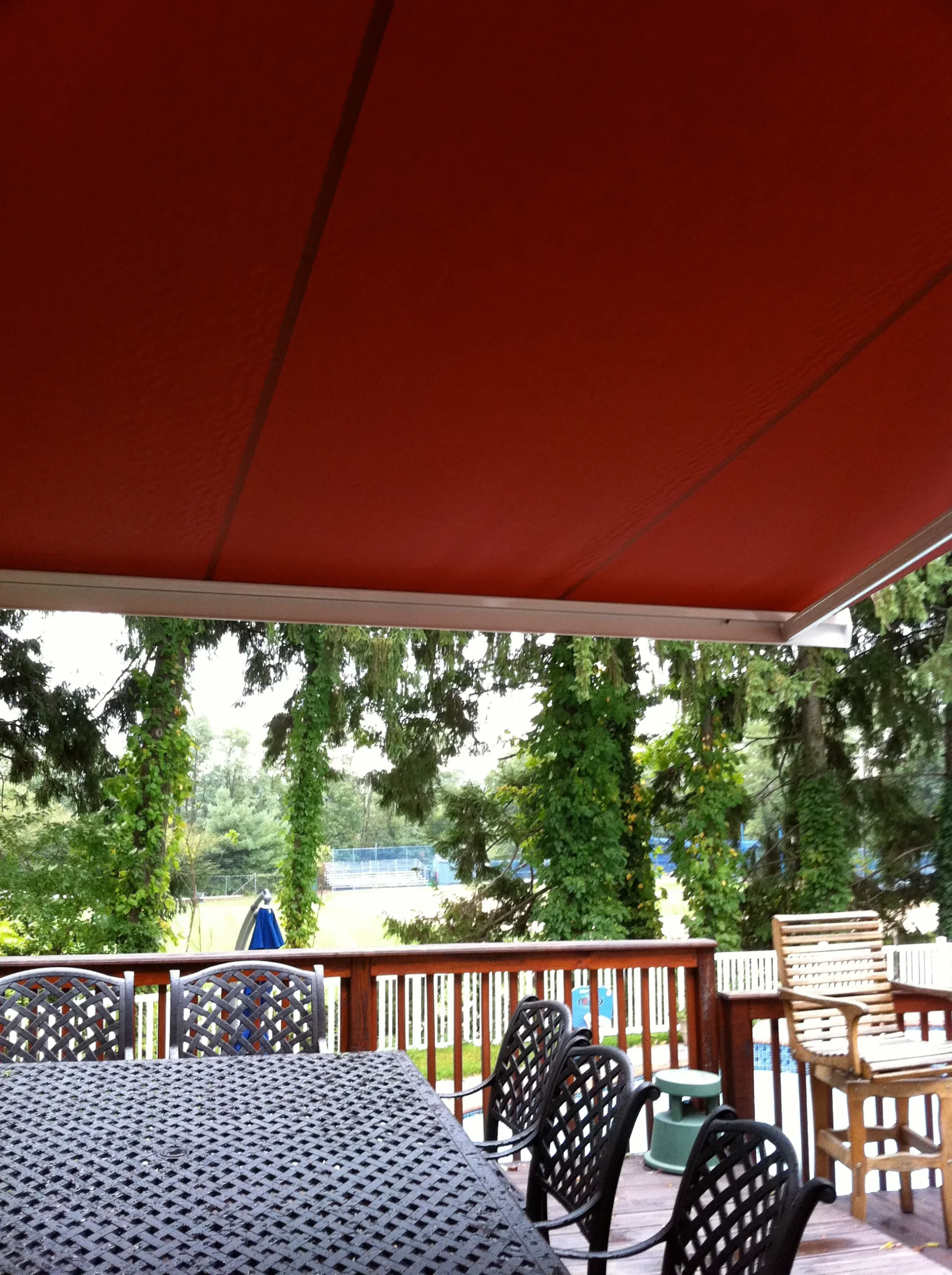 View from under a retractable awning on a deck, offering shade and a clear view of the backyard area.